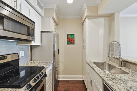 a kitchen with granite countertop a sink stove and refrigerator