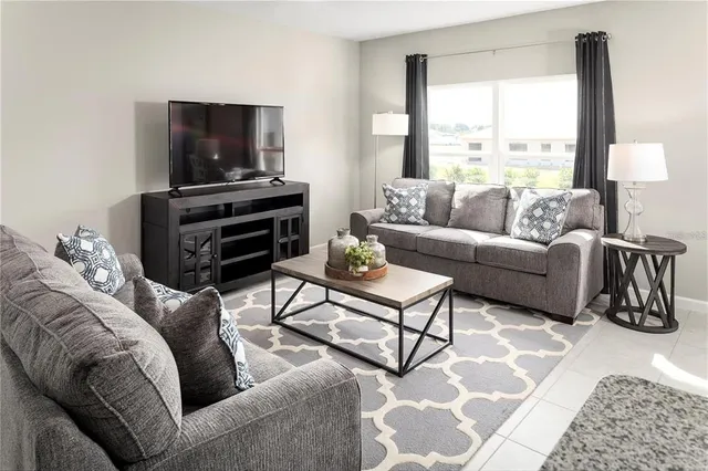 a living room with furniture a flat screen tv and a window
