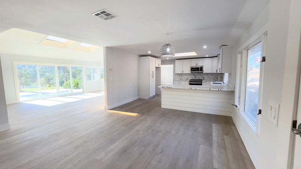 2159 Shire Drive El Cajon, CA 92019 - Photo 7 of 18 a view of a kitchen and an empty room with wooden floor and a kitchen