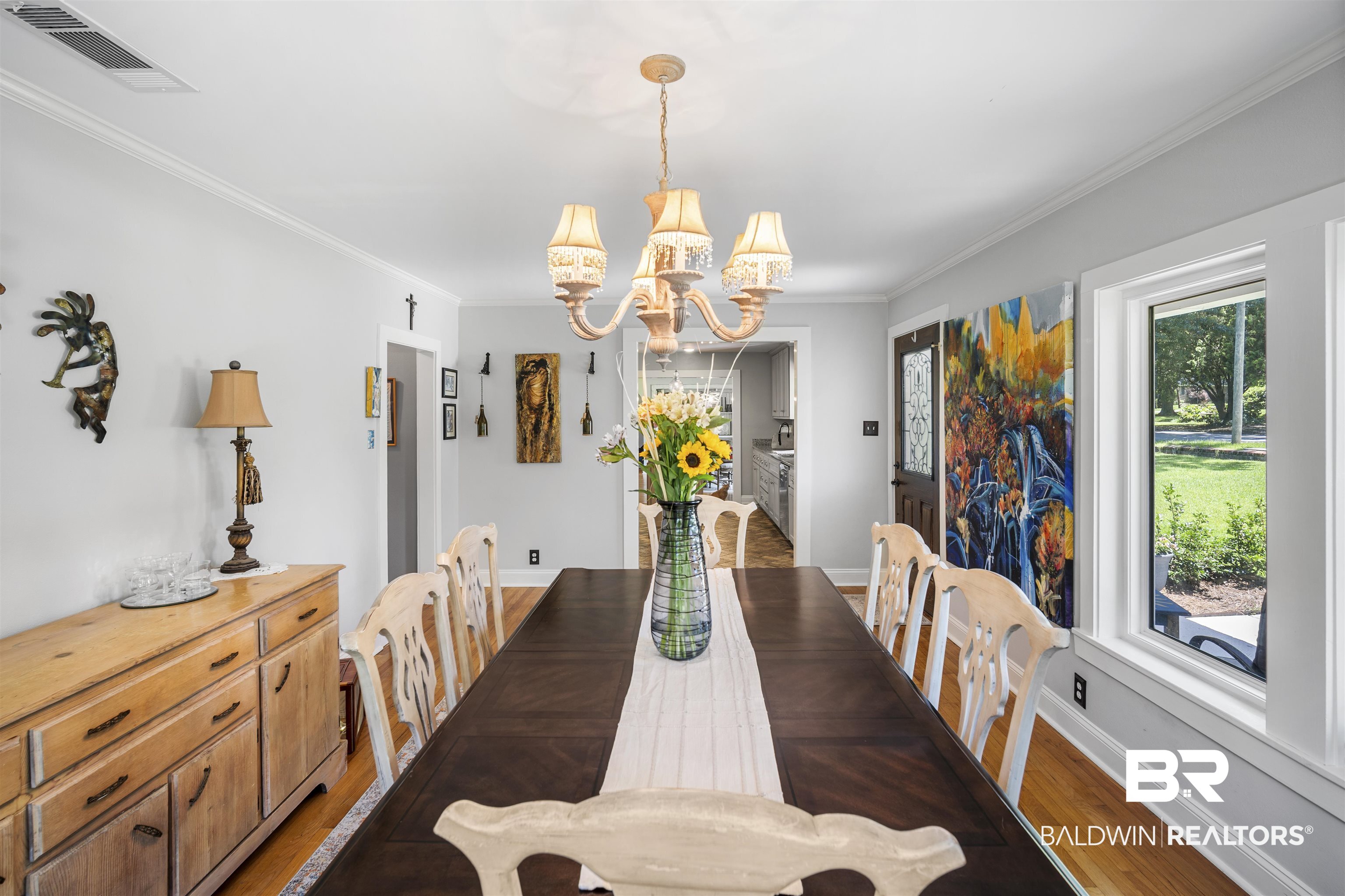 1615 5th Street Daphne, AL 36526 - Photo 3 of 28 Spacious dining area featuring wood-finish flooring, a traditional chandelier, crown molding, and ample natural light from a large window