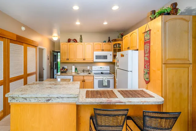 a kitchen with stainless steel appliances granite countertop a refrigerator a stove and a sink