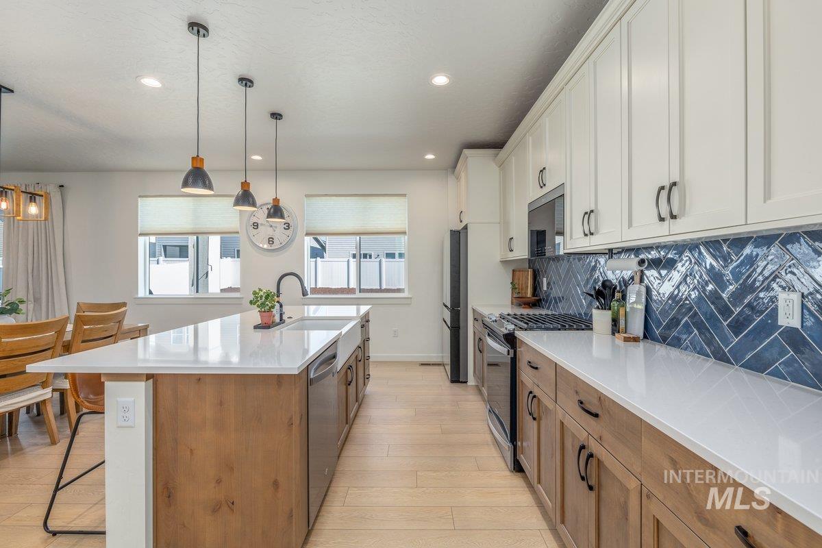 1380 West Chilitna Street Meridian, ID 83642 - Photo 11 of 50 Contemporary kitchen featuring white shaker cabinetry, wood-finish lower cabinets, white countertops, and a blue herringbone tile backsplash