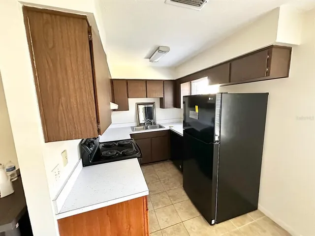 a kitchen with a refrigerator a stove top oven and cabinets