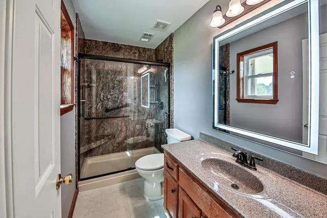 a bathroom with a sink toilet a mirror and shower