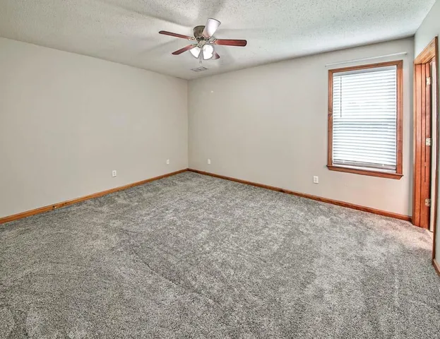 an empty room with a chandelier fan and windows