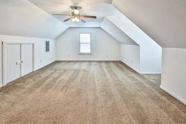 a view of an empty room with chandelier fan