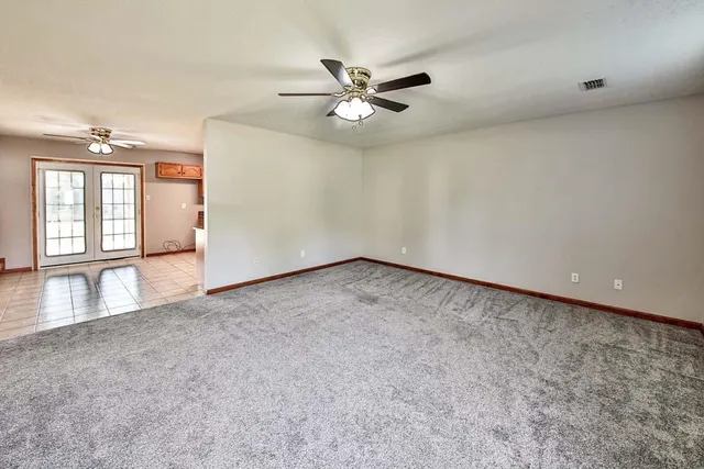 an empty room with windows and fan
