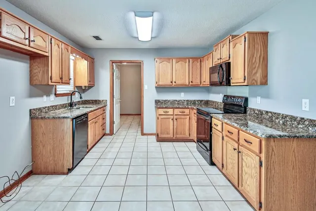 a kitchen with stainless steel appliances granite countertop a stove a sink and a refrigerator