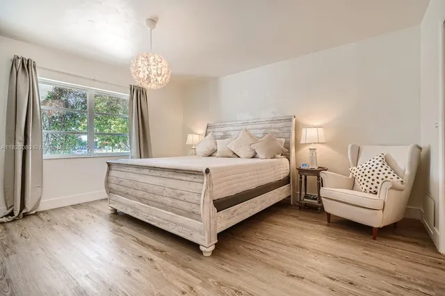 a bedroom with a bed chandelier and a window