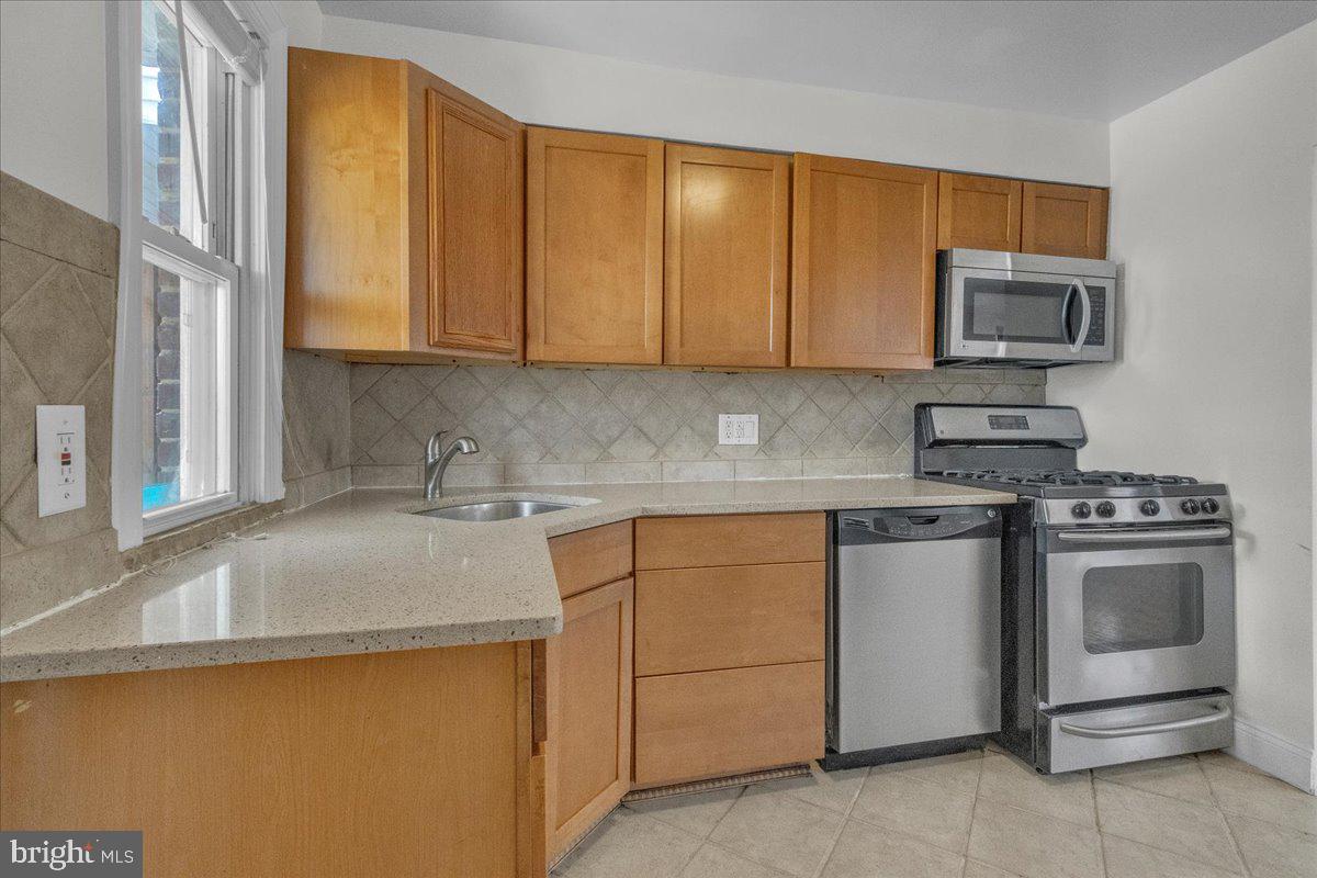 1193 46th Place Southeast Washington, DC 20019 - Photo 3 of 17 a kitchen with stainless steel appliances granite countertop a stove a sink and a microwave
