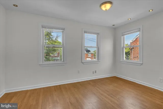 a view of empty room with window and wooden floor