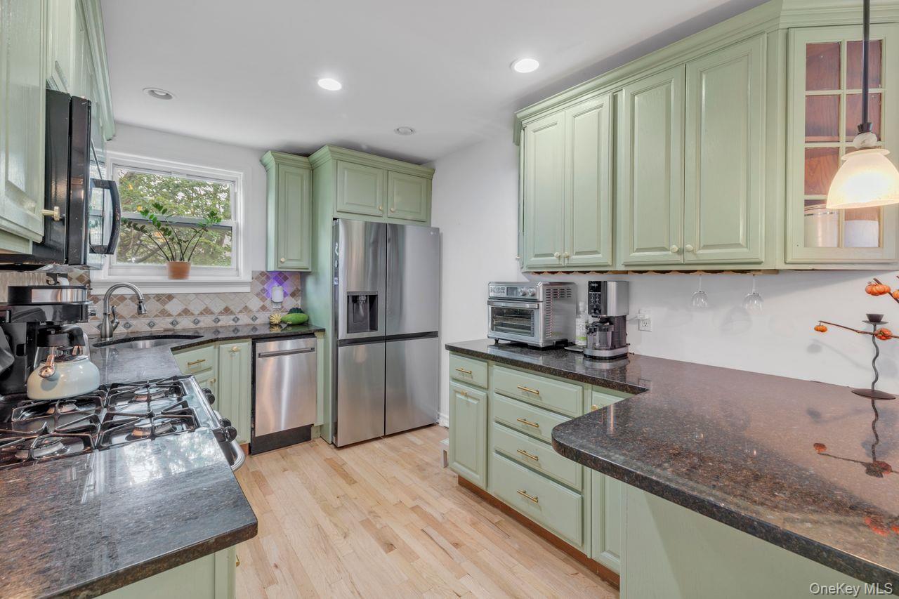 73-20 263rd Street, Unit G Queens, NY 11004 - Photo 9 of 24 a kitchen with stainless steel appliances granite countertop a sink refrigerator and microwave