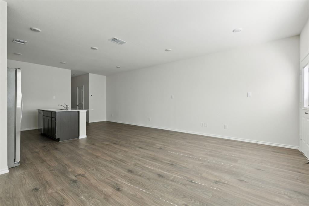 317 Clematis Street Princeton, TX 75407 - Photo 7 of 38 Unfurnished living room featuring dark wood-type flooring and baseboards