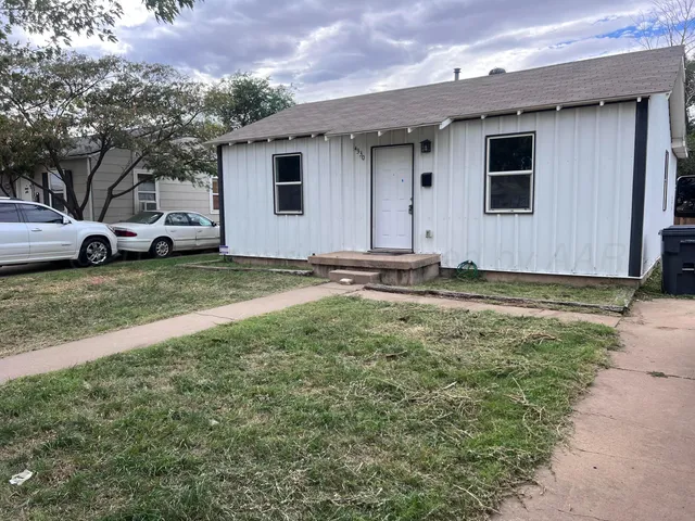 a view of a house with backyard and a car parked in it