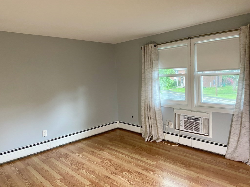 113 Manor Court, Unit 113 Springfield, MA 01118 - Photo 12 of 19 a view of an empty room with a window and wooden floor