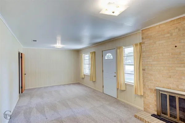 a view of an empty room with a fireplace and a window