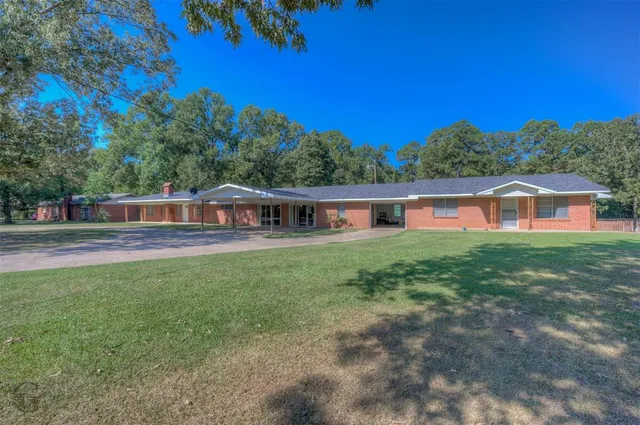 a front view of house with yard and trees in the background