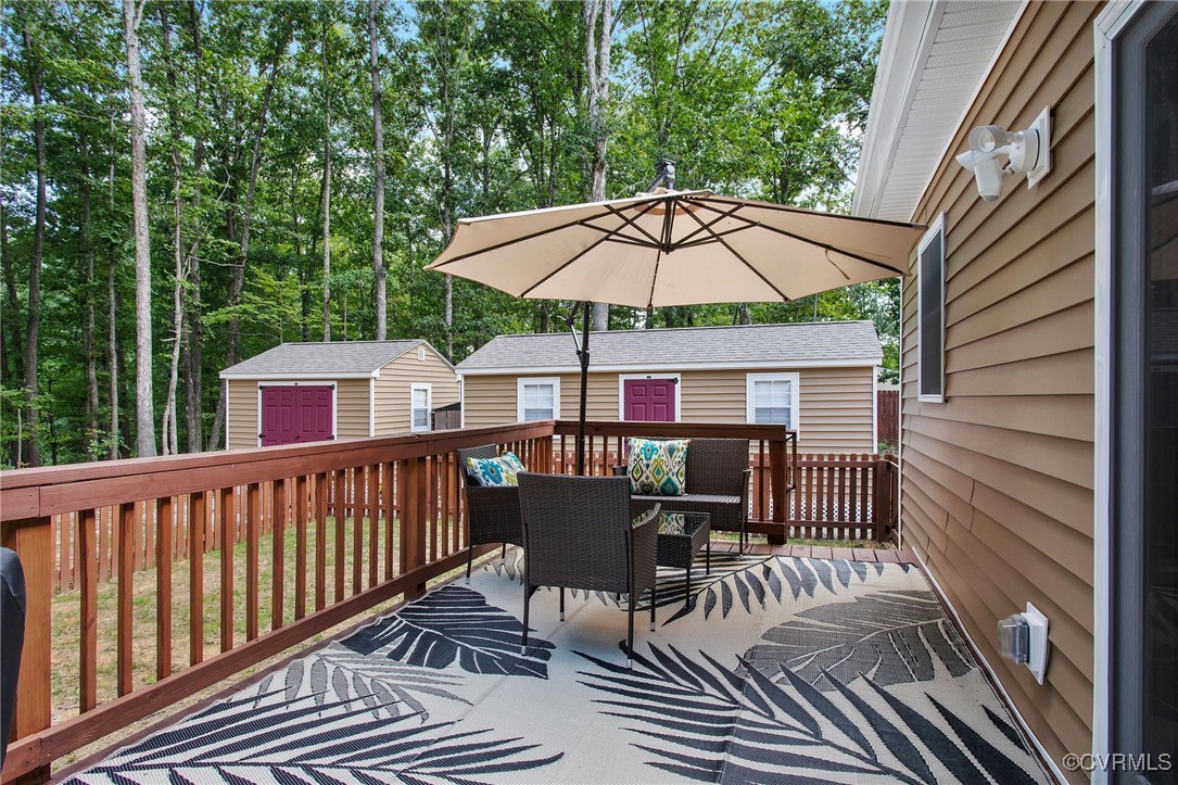 321 Johnson Mill Road Bumpass, VA 23024 - Photo 25 of 33 a view of a roof deck with table and chairs under an umbrella with wooden floor and fence