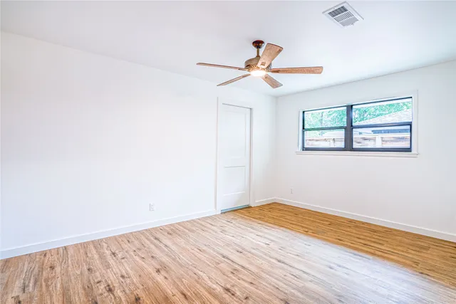 a view of empty room with wooden floor and fan