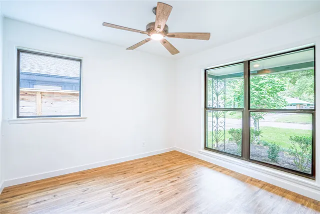 a view of an empty room with a window and wooden floor