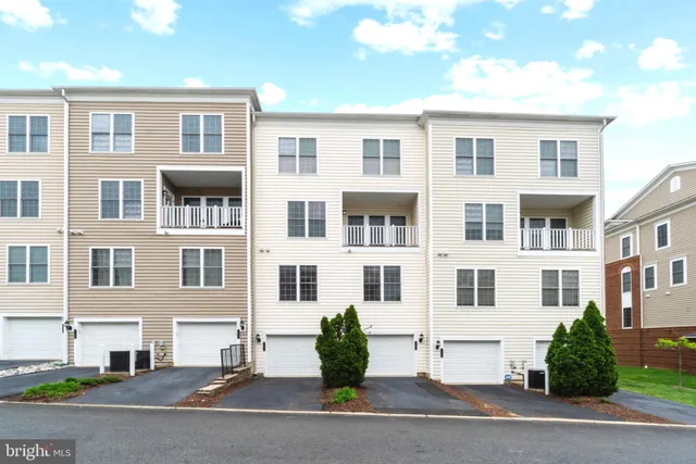 a front view of a residential apartment building with a yard and plants