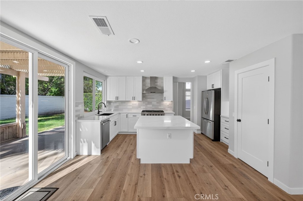 44797 Corte Sanchez Temecula, CA 92592 - Photo 15 of 58 a large white kitchen with wooden floor and stainless steel appliances