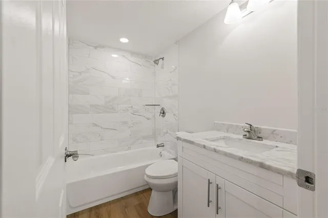 a bathroom with a granite countertop sink a toilet and shower