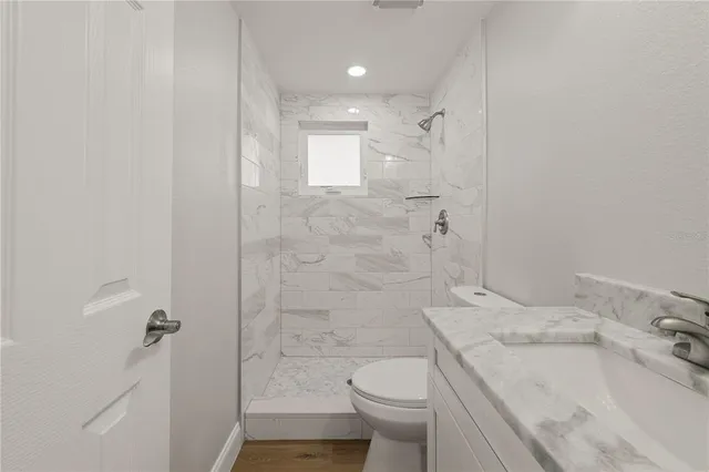 a bathroom with a granite countertop sink a toilet and shower