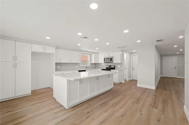a open kitchen with white cabinets and wooden floor