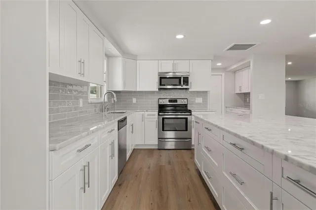 a kitchen with kitchen island granite countertop white cabinets and stainless steel appliances