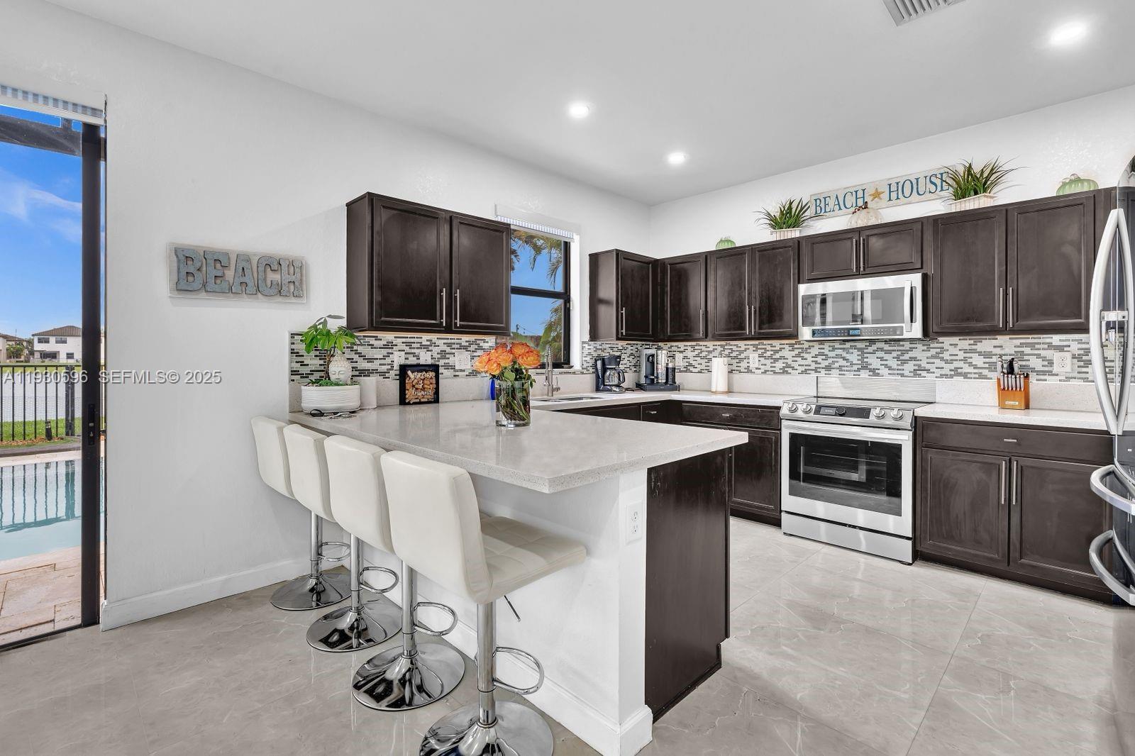 11709 Southwest 253rd Street Homestead, FL 33032 - Photo 12 of 47 a kitchen with stainless steel appliances a stove a sink dishwasher a refrigerator and a dining table with wooden floor
