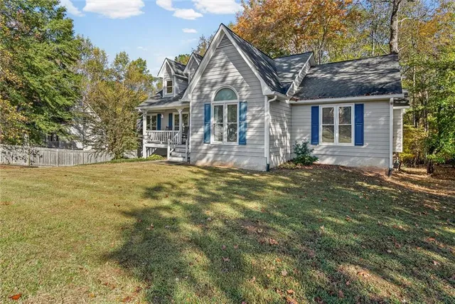 a front view of house with yard and trees in the background