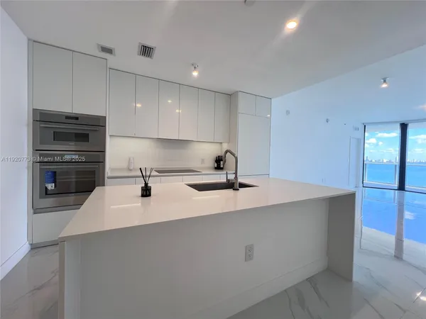 a kitchen with kitchen island a sink stainless steel appliances and cabinets