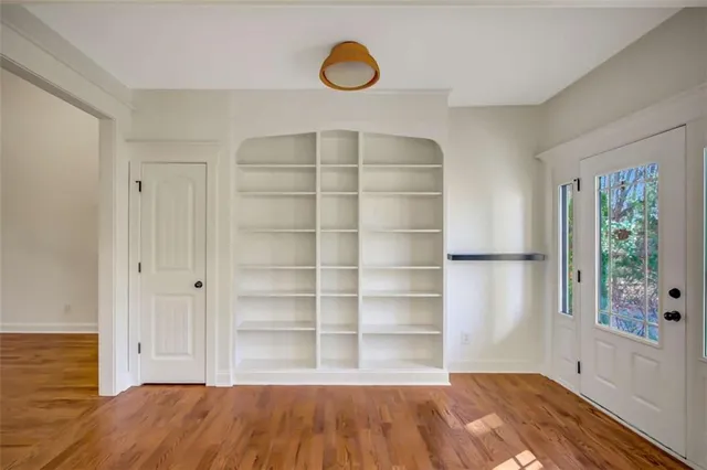 an empty room with wooden floor a fireplace a ceiling fan and windows