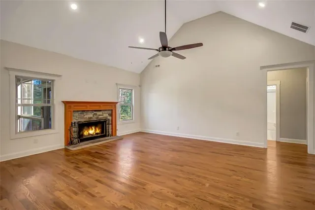 an empty room with wooden floor ceiling fan and window