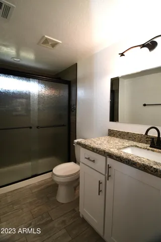 a bathroom with a granite countertop sink a toilet and a mirror