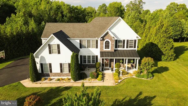 a view of house with yard outdoor seating and covered with trees