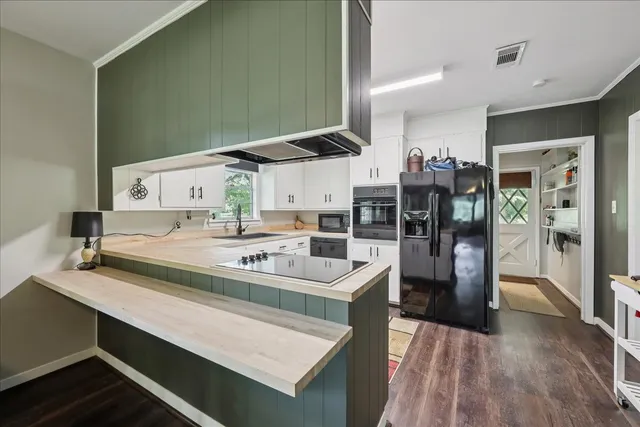 a living room with stainless steel appliances furniture a rug and a kitchen view