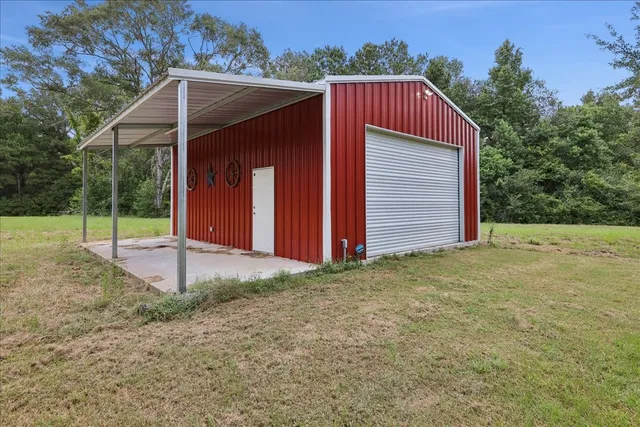 a view of wooden house with a yard and large tree