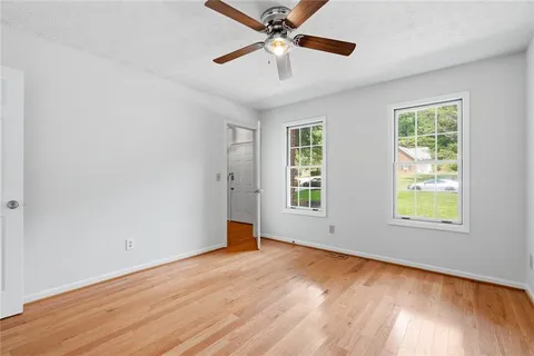 a view of an empty room with a window and wooden floor