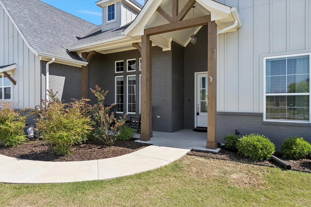 112 Friendship Way Boyd, TX 76023 - Photo 2 of 29 Modern farmhouse exterior featuring board-and-batten siding, dark brick accents, a covered entry with timber posts, and concrete walkway