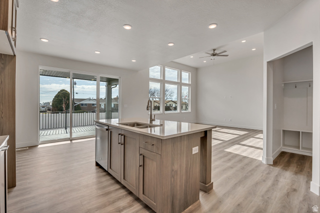 3839 West 825 North, Unit WF18 West Point, UT 84015 - Photo 5 of 22 Kitchen with a kitchen island with sink, light wood-style floors, plenty of natural light, light stone counters, and a textured ceiling