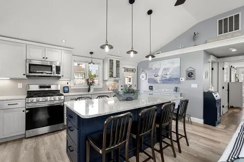 a kitchen with stainless steel appliances granite countertop a kitchen island hardwood floor sink stove dining table and chairs