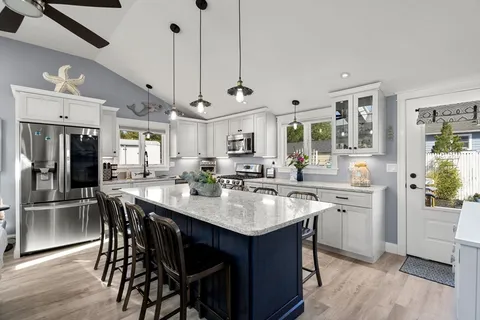 a kitchen with stainless steel appliances granite countertop a table chairs stove and refrigerator