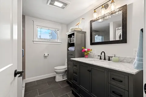 a bathroom with a granite countertop sink vanity mirror and toilet