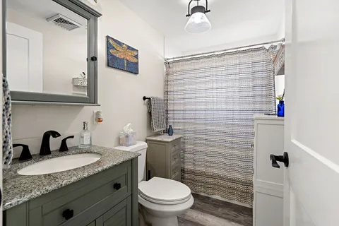 a bathroom with a granite countertop sink toilet and shower