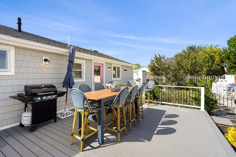 a view of a patio with table and chairs with wooden floor and fence