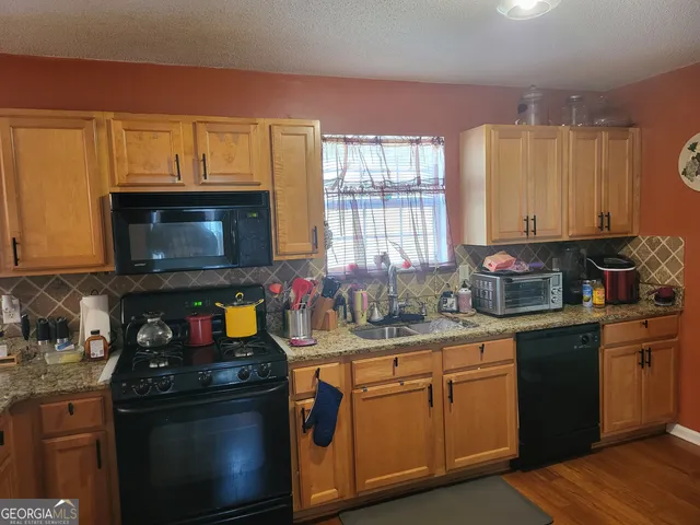 a kitchen with stainless steel appliances granite countertop a stove a sink and a microwave