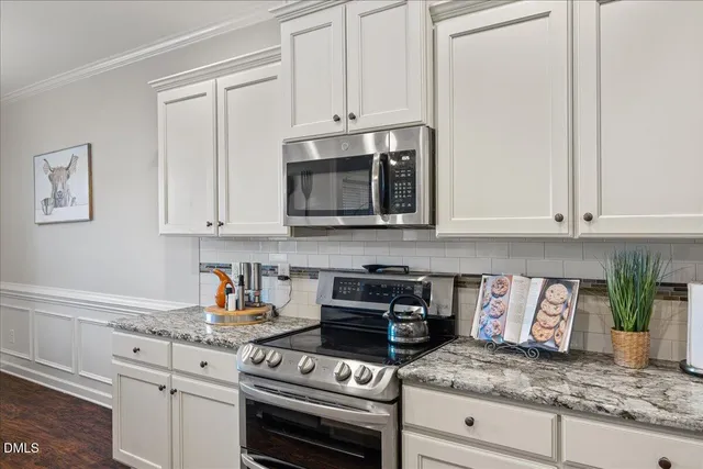 a kitchen with granite countertop white cabinets and stainless steel appliances