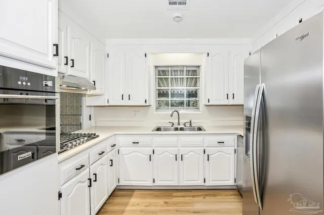 a kitchen with stainless steel appliances white cabinets and a refrigerator